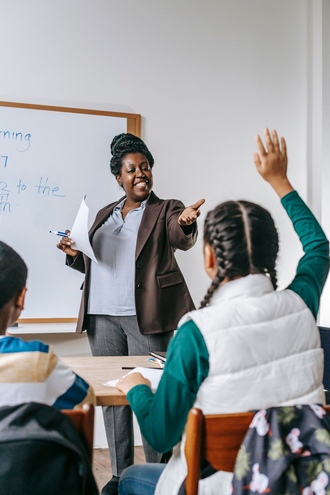 A teacher encouraging a young girl to speak up and participate during class, building her confidence